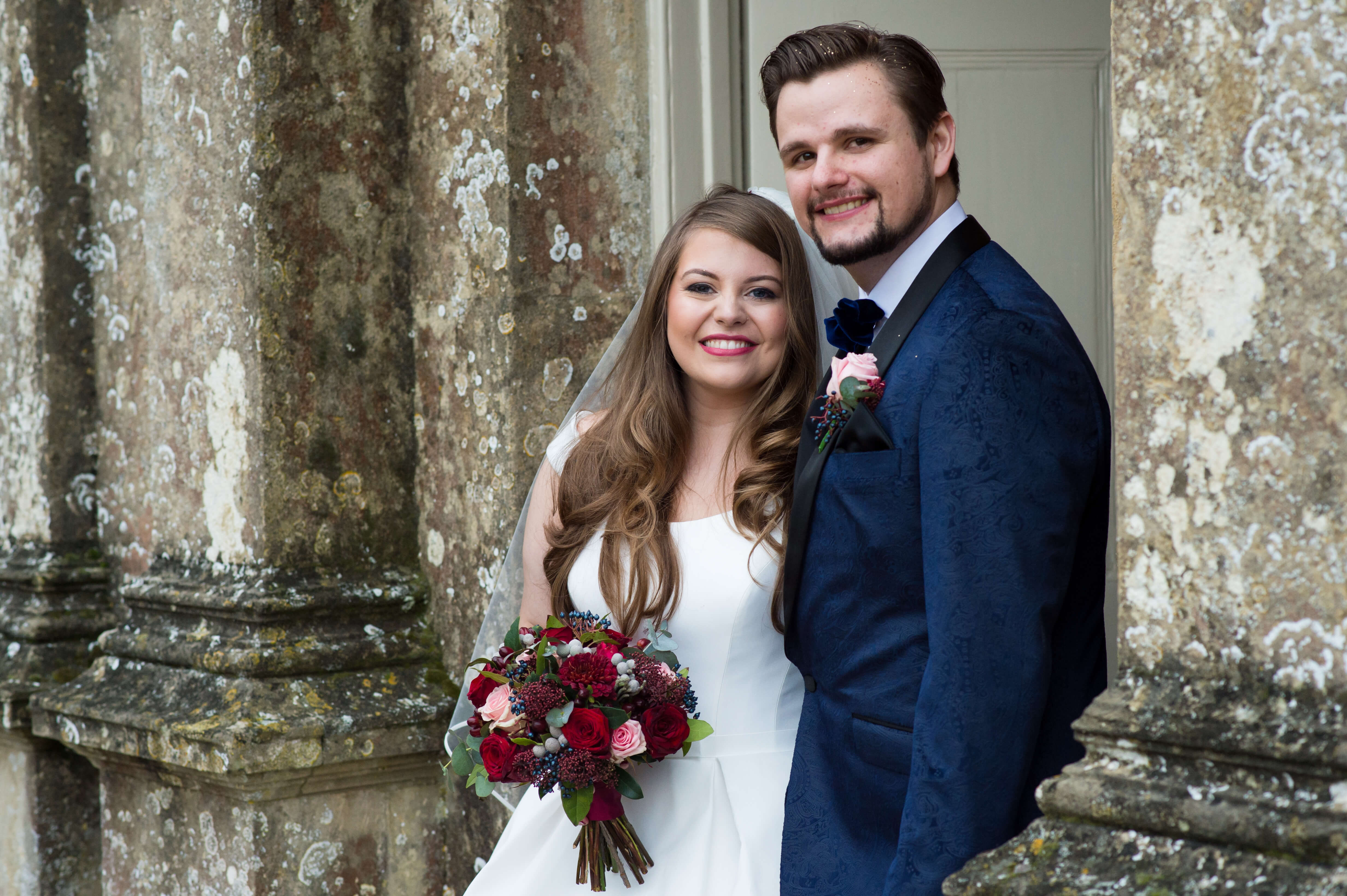 A bride carrying a wedding bouquet by sweet peas of great tew standing next to her groom